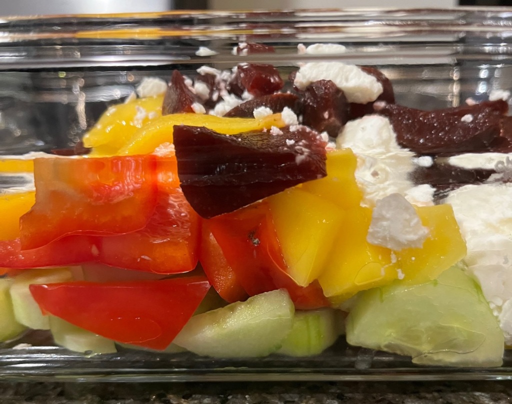 Beet, mango, red pepper, cucumber, goat cheese salad seen from the side